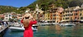 Holidays in Portofino, Italy. Back view of beautiful girl in red dress enjoying view of the picturesque village of Portofino with Royalty Free Stock Photo