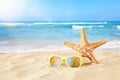 Holidays. sand beach, sunglasses and starfish in front of summer sea background with copy space Royalty Free Stock Photo