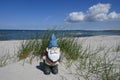 Holidays by the sea .. Dunes, white sandy beach and a little garden gnome with bare bottom. Royalty Free Stock Photo