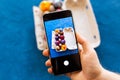 Holidays, tradition, technology and people concept - close up of man hands with smartphone taking picture of colored easter eggs