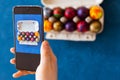 Holidays, tradition, technology and people concept - close up of man hands with smartphone taking picture of colored easter eggs