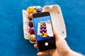 Holidays, tradition, technology and people concept - close up of man hands with smartphone taking picture of colored easter eggs
