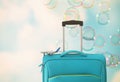 Holidays. travel concept. blue suitcase and airplane toy infront of sky with soap bubbles background Royalty Free Stock Photo