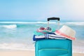 Holidays. travel concept. blue suitcase with female hat, flip flips, sunglasses and beach towel in front of tropical background Royalty Free Stock Photo