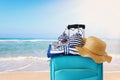 Holidays. travel concept. blue suitcase with female hat, sunglasses bikini and beach towel in front of tropical background Royalty Free Stock Photo