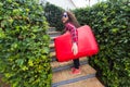 Holidays, travel, people concept - young woman with heavy red suitcase