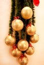 Holidays wreath of fir branches with Christmas baubles. Twigs pine, golden balls and red bows as Christmas decorations on wall. Royalty Free Stock Photo