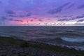 Holland - Sunset over the stormy sea. A stone rampart jutting out into the sea. in the foreground sand and green grass Royalty Free Stock Photo