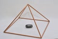 A hollow copper pyramid with a magnet or magnet inside. White background. Selective focus. Brazil, South America