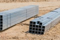 Hollow metal beams laying on sandy ground