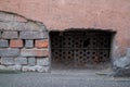 Basement window sealed with rusty metal perforated plates in facade of old house with shabby facing, on left brickwork emerges Royalty Free Stock Photo