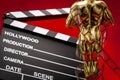 Hollywood film awards concept with shiny metallic movie award wrapped in celluloid film strip on red carpet with clapper board Royalty Free Stock Photo