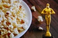 Hollywood Golden Oscar Academy award statue in medical mask on pop corn background. Success and victory concept. Oscar ceremony in