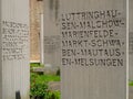 The Holocaust memorial with written stele and green grass and roses