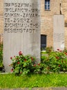 The Holocaust memorial with written stele and green grass and roses