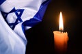 Holocaust Remembrance Day. Yom HaShoah. Bright Burning Candle and the official flag of Israel on a dark grey background. Royalty Free Stock Photo