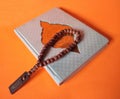 The Holy Al quran and tasbeh or Moslem prayer beads on orange background.