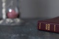 Holy bible book with an hourglass in the background, closeup Royalty Free Stock Photo
