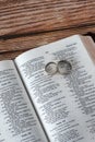 Holy Bible Book with 2 wedding rings on wooden table, copy space, vertical shot Royalty Free Stock Photo