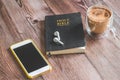 The Holy Bible with headphones, a phone and a hot cup of coffee. Reading the bible. Royalty Free Stock Photo