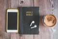 The Holy Bible with headphones, a phone and a hot cup of coffee. Reading the bible. Royalty Free Stock Photo