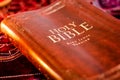 Holy Bible King James Version with pressed decorative leather cover on table with soft flickering candlelight