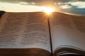 Holy Bible open at sunset with highlight on Malachi 4:2. Background with sun and clouds