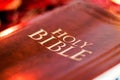 Holy Bible with pressed decorative leather cover on table with soft flickering candlelight Royalty Free Stock Photo