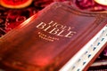 Holy Bible with pressed decorative leather cover on table with soft flickering candlelight Royalty Free Stock Photo