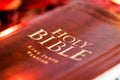 Holy Bible with pressed decorative leather cover on table with soft flickering candlelight Royalty Free Stock Photo