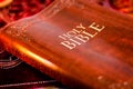 Holy Bible with pressed decorative leather cover on table with soft flickering candlelight Royalty Free Stock Photo