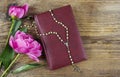 Holy Bible, rosary and lush pink peonies