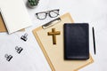 Holy Bible with a wooden cross, glasses, cactus over the marble background. Royalty Free Stock Photo