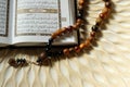 Holy book for muslims,Koran and rosary on wooden engraving background.