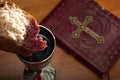 Holy Communion and Easter concept with The Holy Bible in the background and bread dipped in red wine from a silver chalice Royalty Free Stock Photo