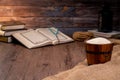 Holy Quran and a grain of rice in a wooden bowl in the sack on a wooden table, Islamic zakat concept.