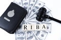 Holy Quran, judge gavel, money banknotes and wooden cubes with text RIBA Royalty Free Stock Photo