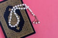 The Holy Quran with rosary beads isolated on pink background