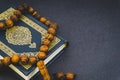 Holy Quran with tasbih or rosary beads over black background