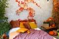 Home autumn decor. Cozy fall bedroom interior bed with orange pillows, flowers, pumpkins, Autumn decoration Royalty Free Stock Photo