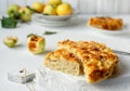Home baked apple pie served on cutting board, yellow apples on white background, closeup view