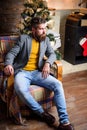 Home is best place. Man bearded hipster relax sit armchair near christmas tree. Feel like home. Man mature confident guy Royalty Free Stock Photo