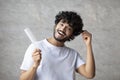 Home care after shower, morning routine procedure. Cheerful indian man with comb touching curly healthy hair