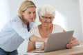 Home carer and elderly woman using laptop