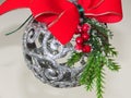 Home Christmas decoration. A silver ball. small green Christmas tree branch, red ribbon and mistletoe on light blurred background. Royalty Free Stock Photo