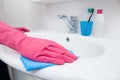 Home cleaning in the bathroom. A woman in pink gloves cleaning a white sink with a sponge and spray and detergent. Hygiene at home Royalty Free Stock Photo