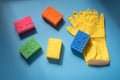 Home cleaning supplies: sponges and yellow rubber gloves on blu background Royalty Free Stock Photo