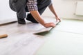 Repair, building and home concept - close up of male hands intalling wood flooring Royalty Free Stock Photo