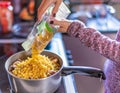 Home cook adding pasta to a saucepan of mushrooms and stock