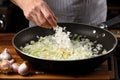 home cook stirring freshly diced onions into pan